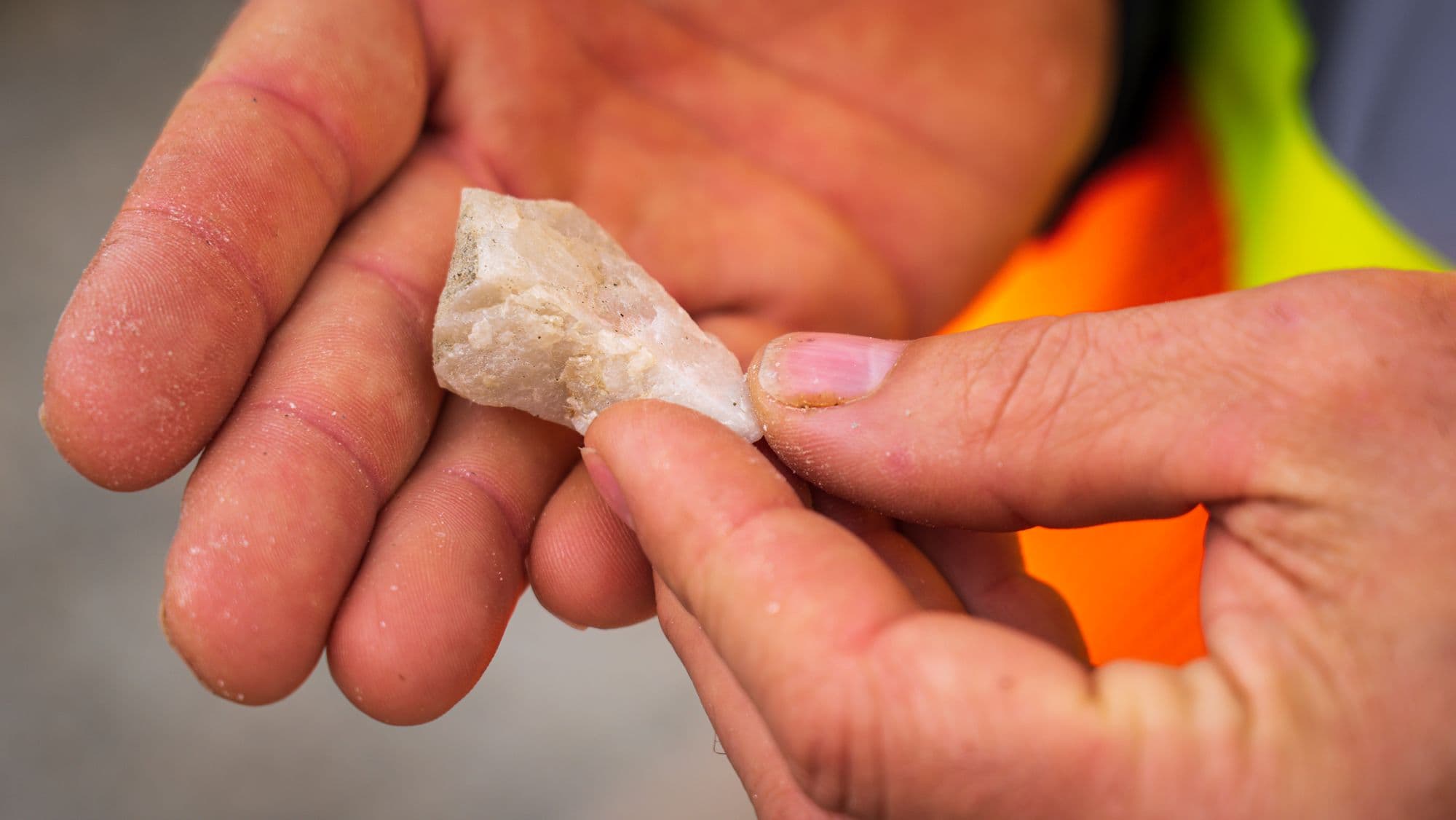 Hand holding a small white quartz rock sample